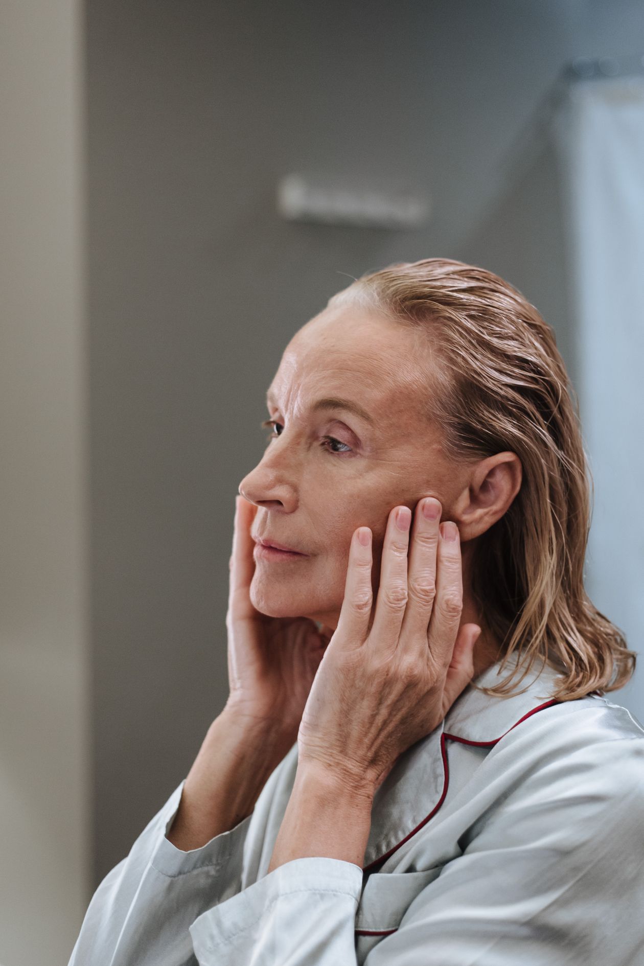 Femme mature appliquant de la crème sur son visage avec un sourire