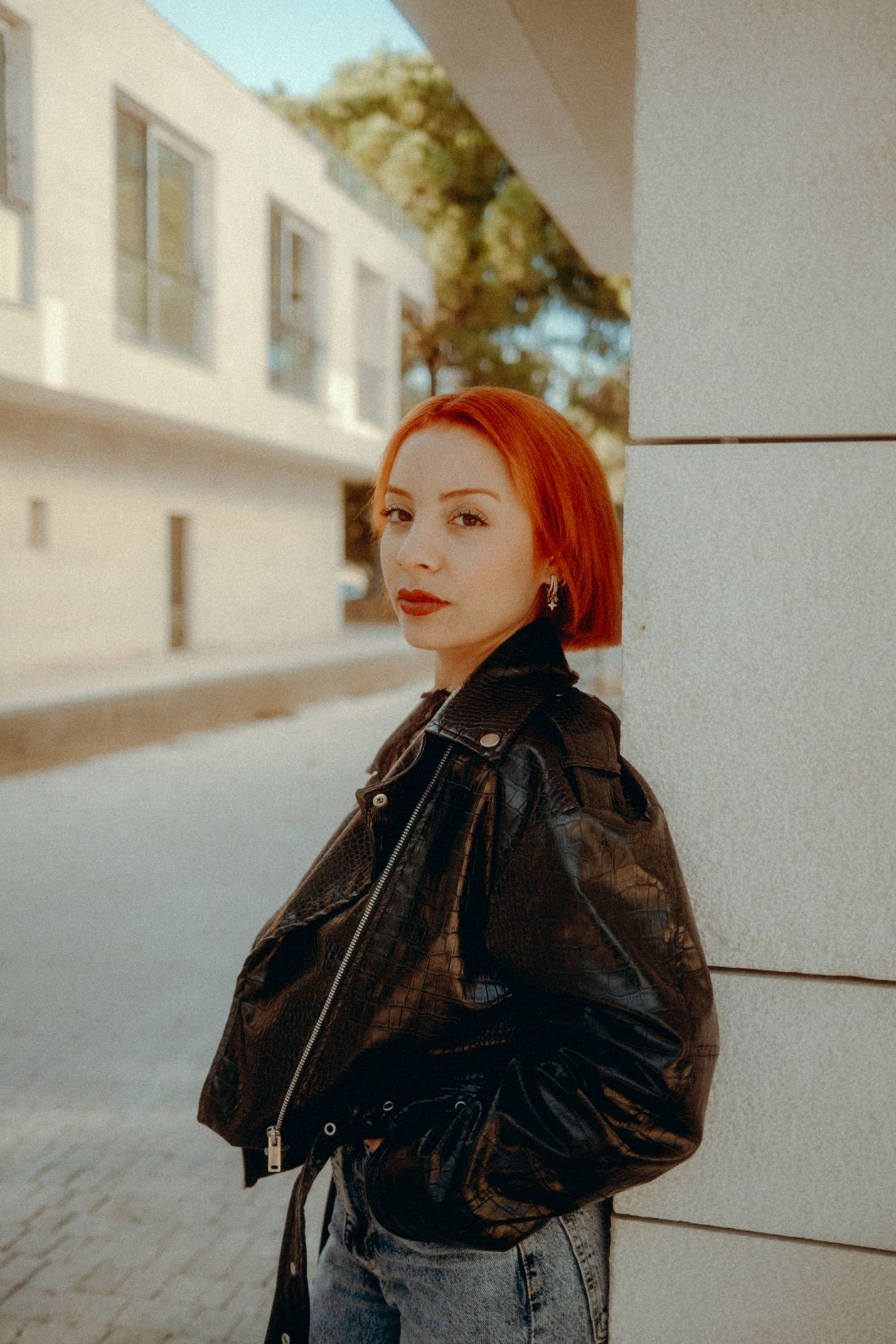 Femme portant une veste en cuir noir avec jean droit et sneakers blanches